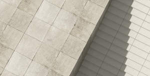 the image shows off a sidewalk that is grey in color and tiled, beside it to the right of the screen are stairs that is half dark grey and white.