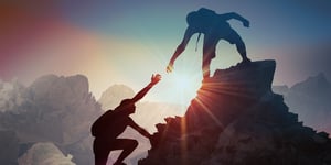 Two climbers helping each other up a mountain 