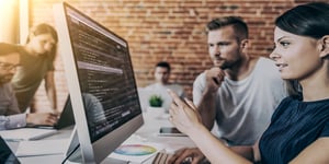 Man and woman software developers at work looking at code on computer