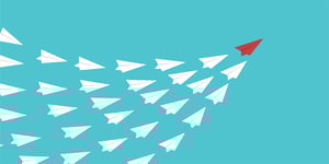 Group of paper airplanes being led by one red paper airplane