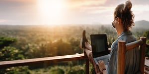 Woman working outside on computer with sunrise