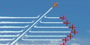 Red airplanes in the sky one going in a different direction