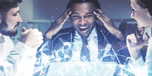 Man at desk surprised and smiling with collogues 