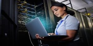 Woman in cybersecurity on laptop network data center