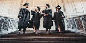 Four graduates standing on staircase