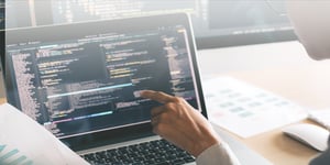 Person pointing at laptop screen that has code written on it for software development 