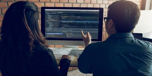 Man and Woman looking at code on computer