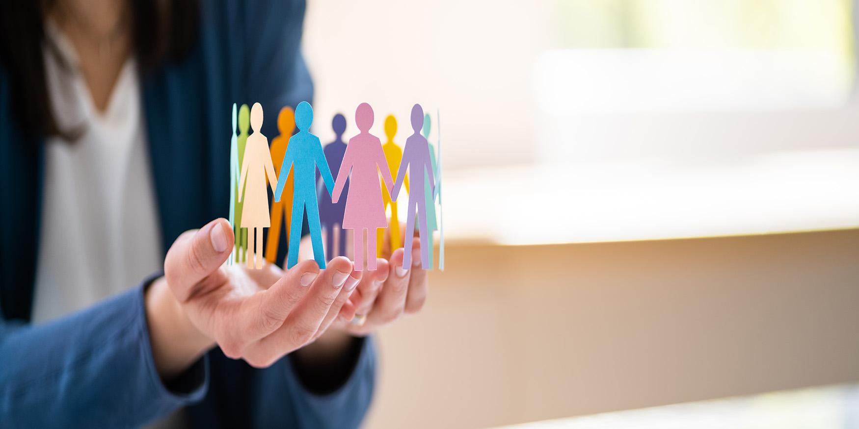 Hands holding multicolored paper chain of people 