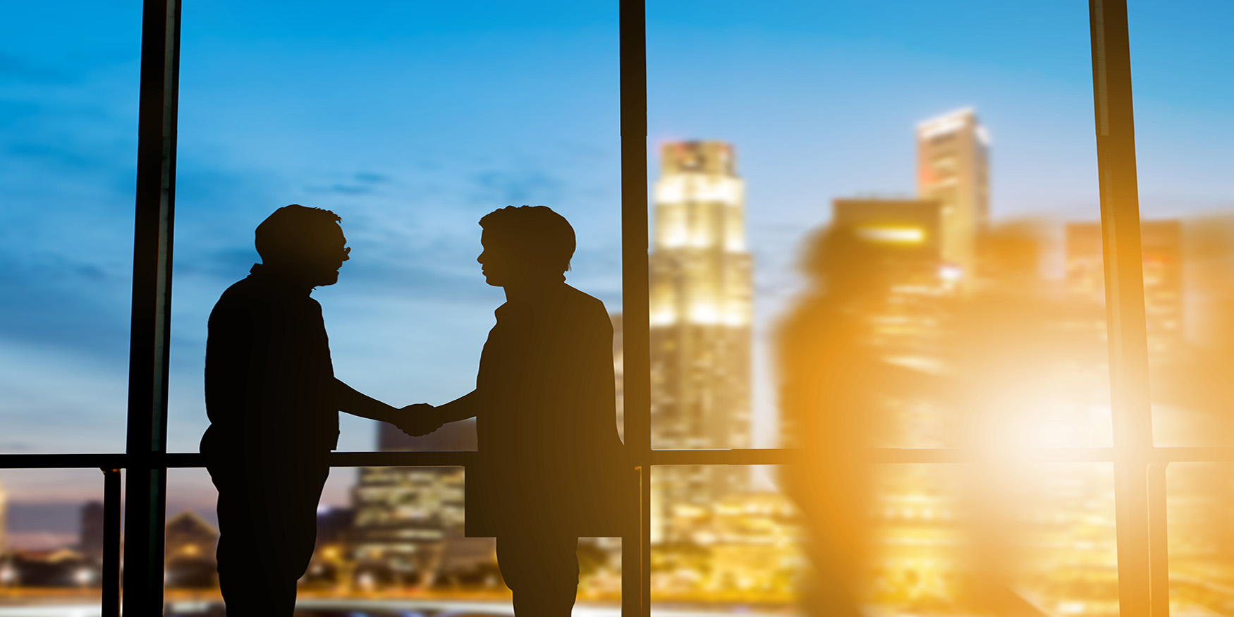 silhouette businessmen shake hands finishing deal